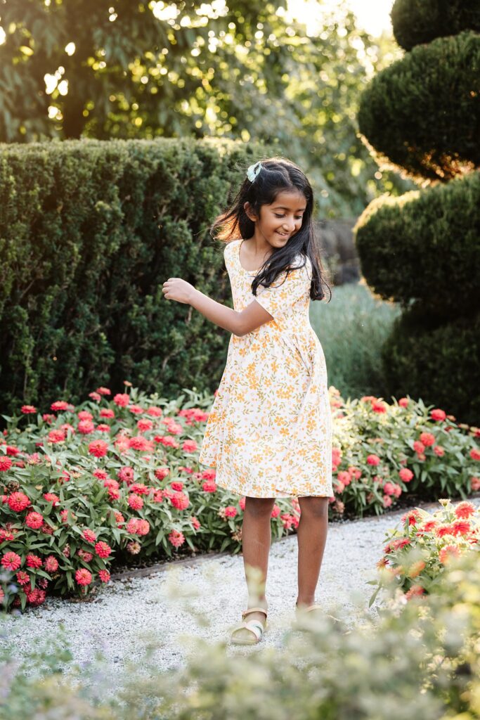 young girl twirling in a garden